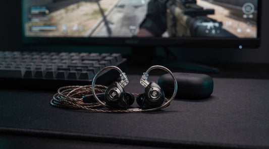 Gaming IEMs on a desk with mechanical keyboard and ultrawide monitor